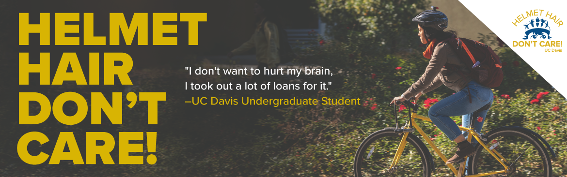 A student wearing a bike helmet biking through campus