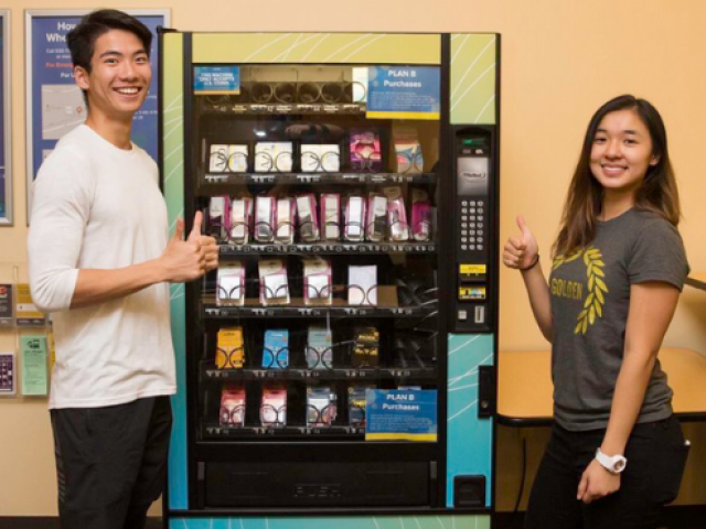 photo of two students giving a thumbs up next to the Wellness to Go vending machine