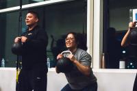 Smiling students holding kettlebells in a squat at the ARC